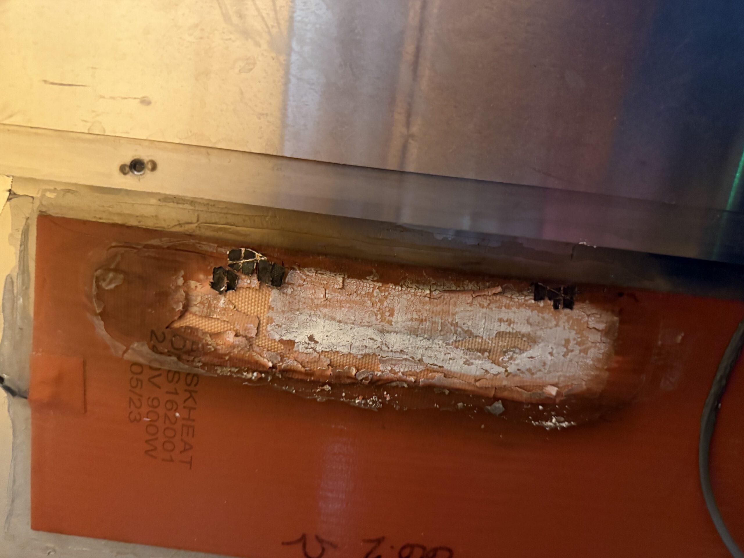 Damaged ultrasonic cleaner heating blanket showing visible burn and heat damage